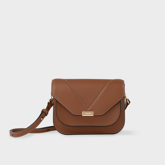 Caramel leather crossbody bag in smooth calfskin with flap closure, Santoir Fortuna bag with structured silhouette, adjustable strap and gold finished solid brass hardware, handcrafted in Spain.