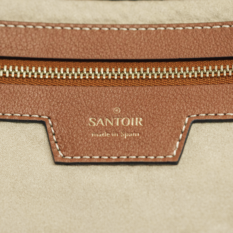 Embossed Santoir logo on smooth caramel leather interior, highlighting fine craftsmanship and luxury details of the Luna crescent handbag, made in Spain.