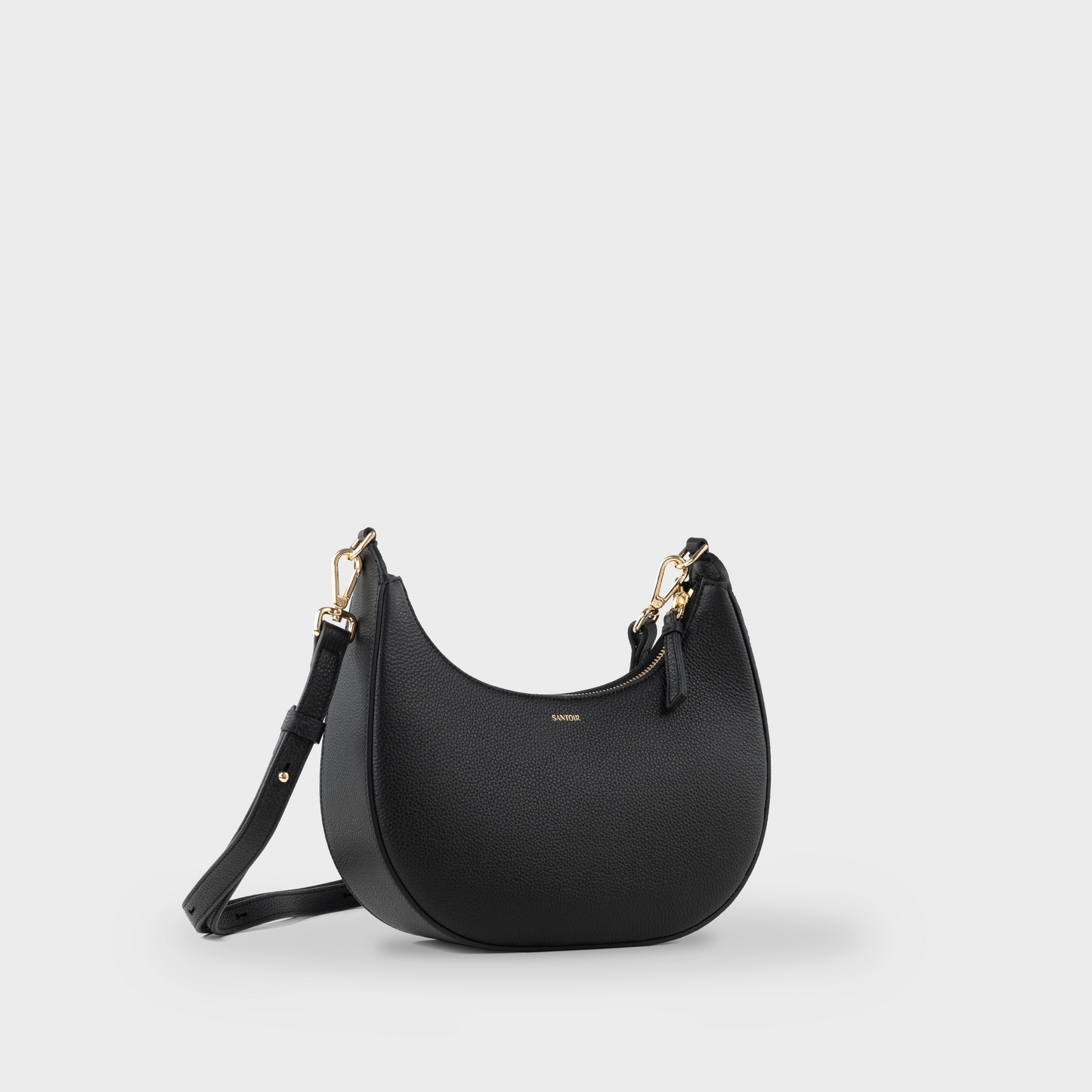Black crossbody crescent bag with adjustable long strap, Santoir Luna in pebbled calfskin leather, structured everyday to night luxury handbag made in Spain.