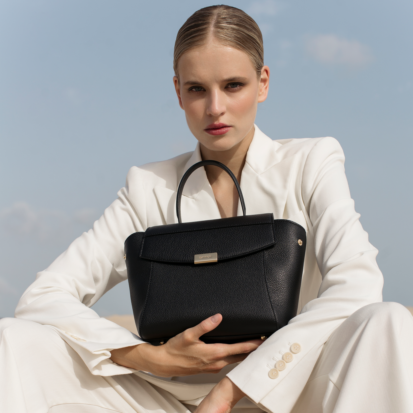 Black leather mini top handle bag worn on arm, Santoir Mini Boss in pebbled calfskin with structured silhouette, elegant day-to-night luxury accessory handcrafted in Spain.