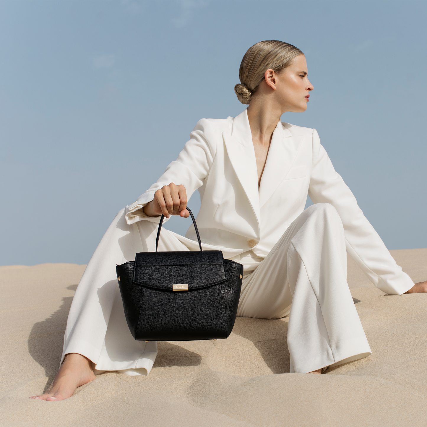 Black leather mini top handle bag worn on arm, Santoir Mini Boss in pebbled calfskin with structured silhouette, elegant day-to-night luxury accessory handcrafted in Spain.
