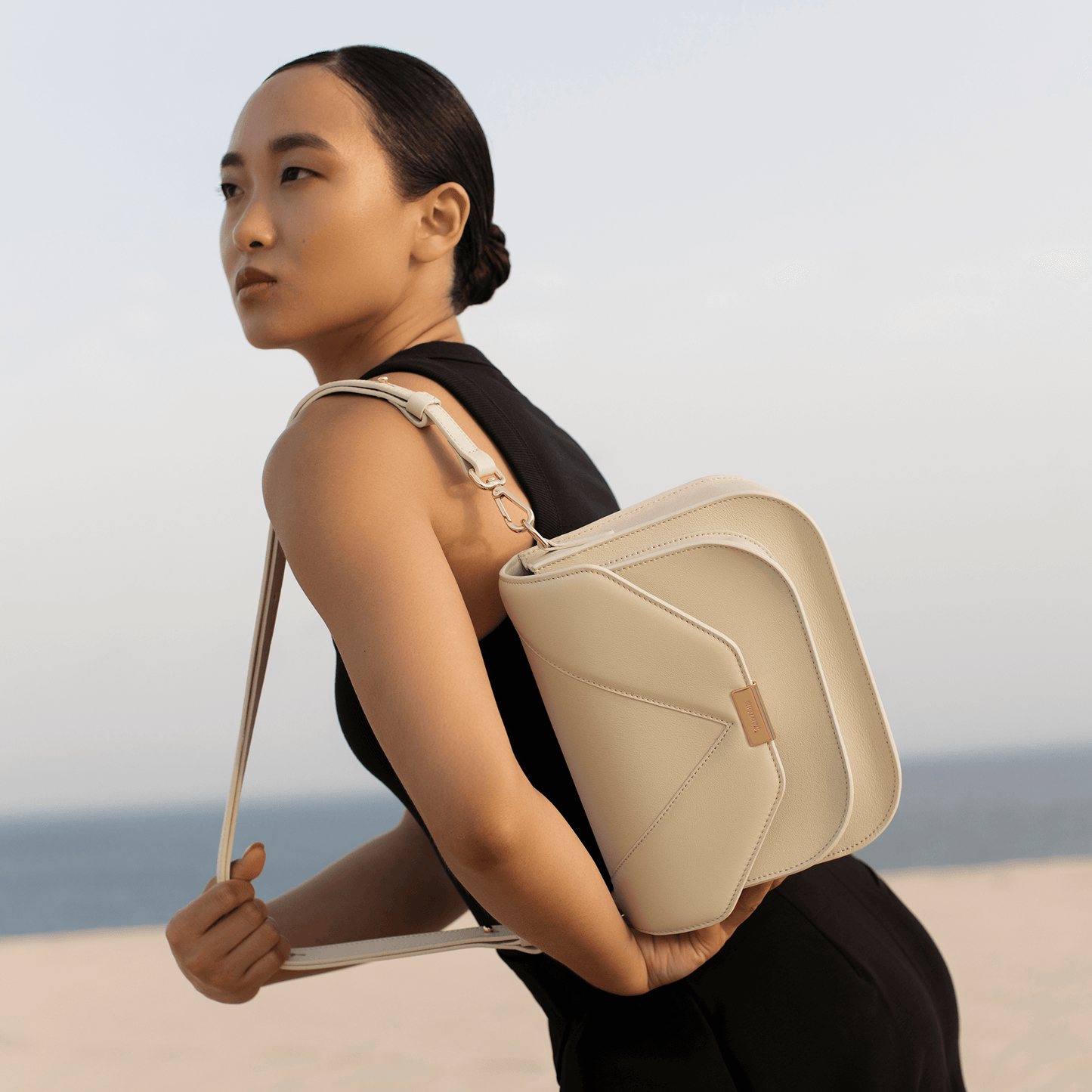 Neutral ivory leather crossbody bag styled casually for everyday wear, Santoir Fortuna bag in smooth off-white calfskin with structured saddle-inspired shape.