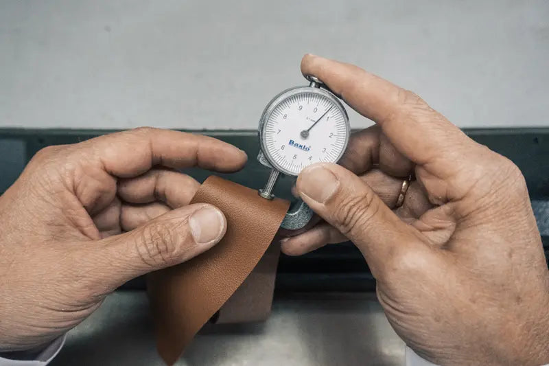 Artisan hands measuring calfskin thickness in workshop