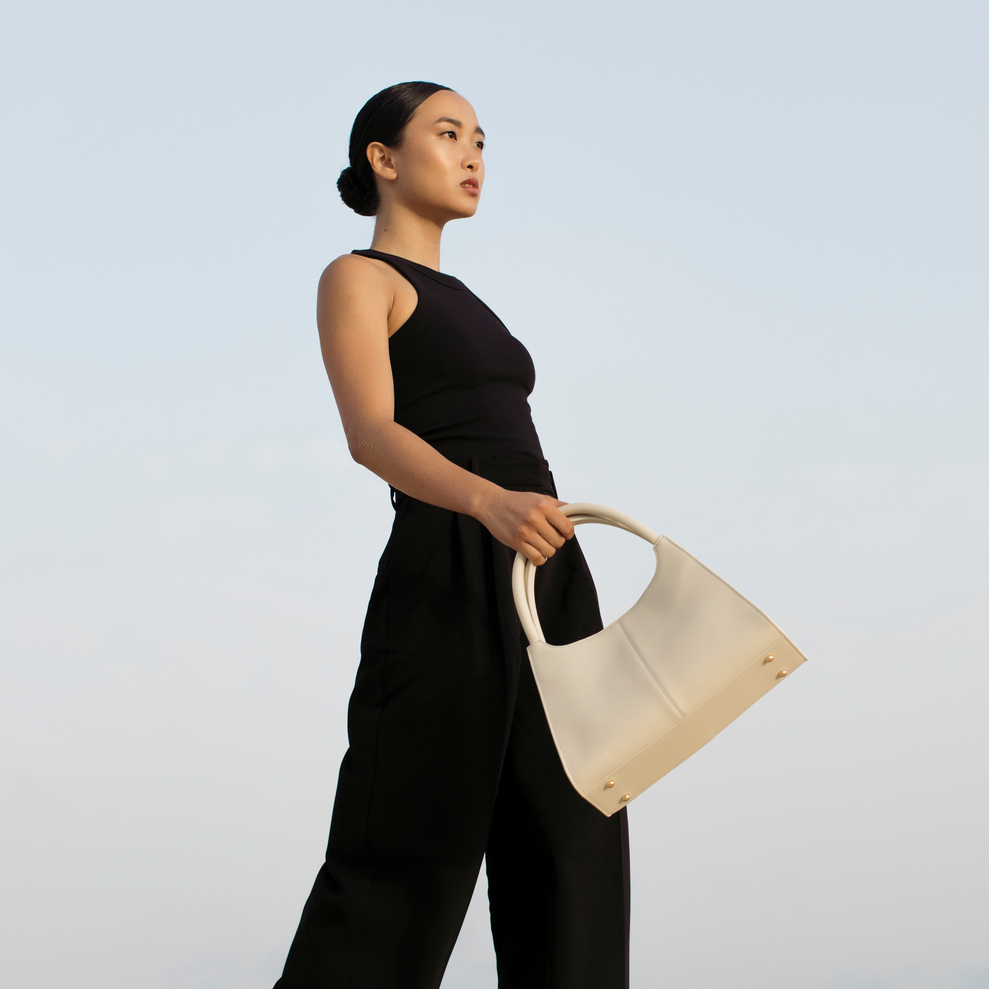 Elegant ivory smooth leather handbag styled on model’s hand, structured trapezoid silhouette in soft neutral calfskin, Santoir Classic 5 for modern women.
